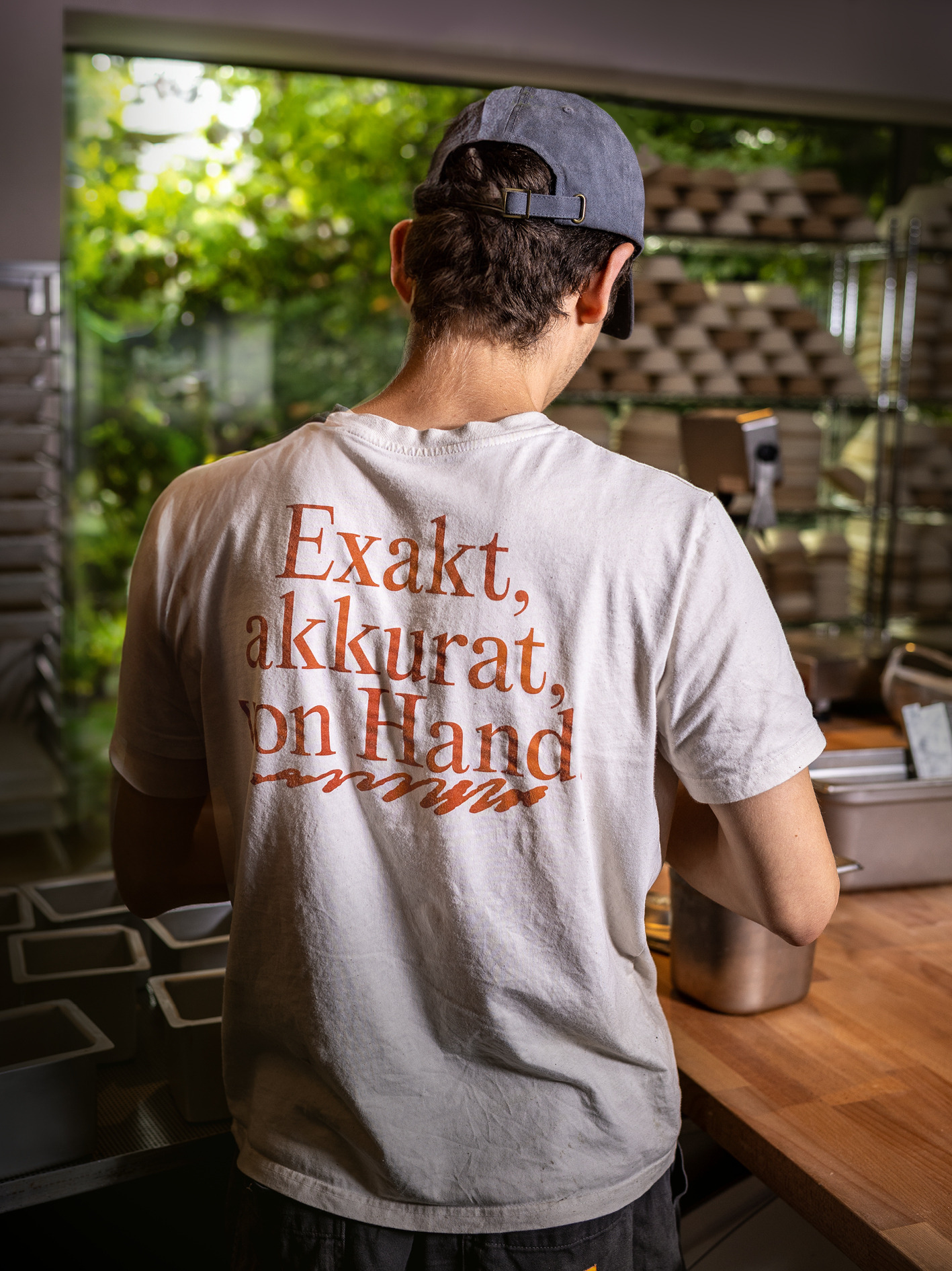 Ein Mitarbeiter von hinten mit bedrucktem T-Shirt am Tresen der Brotique.
