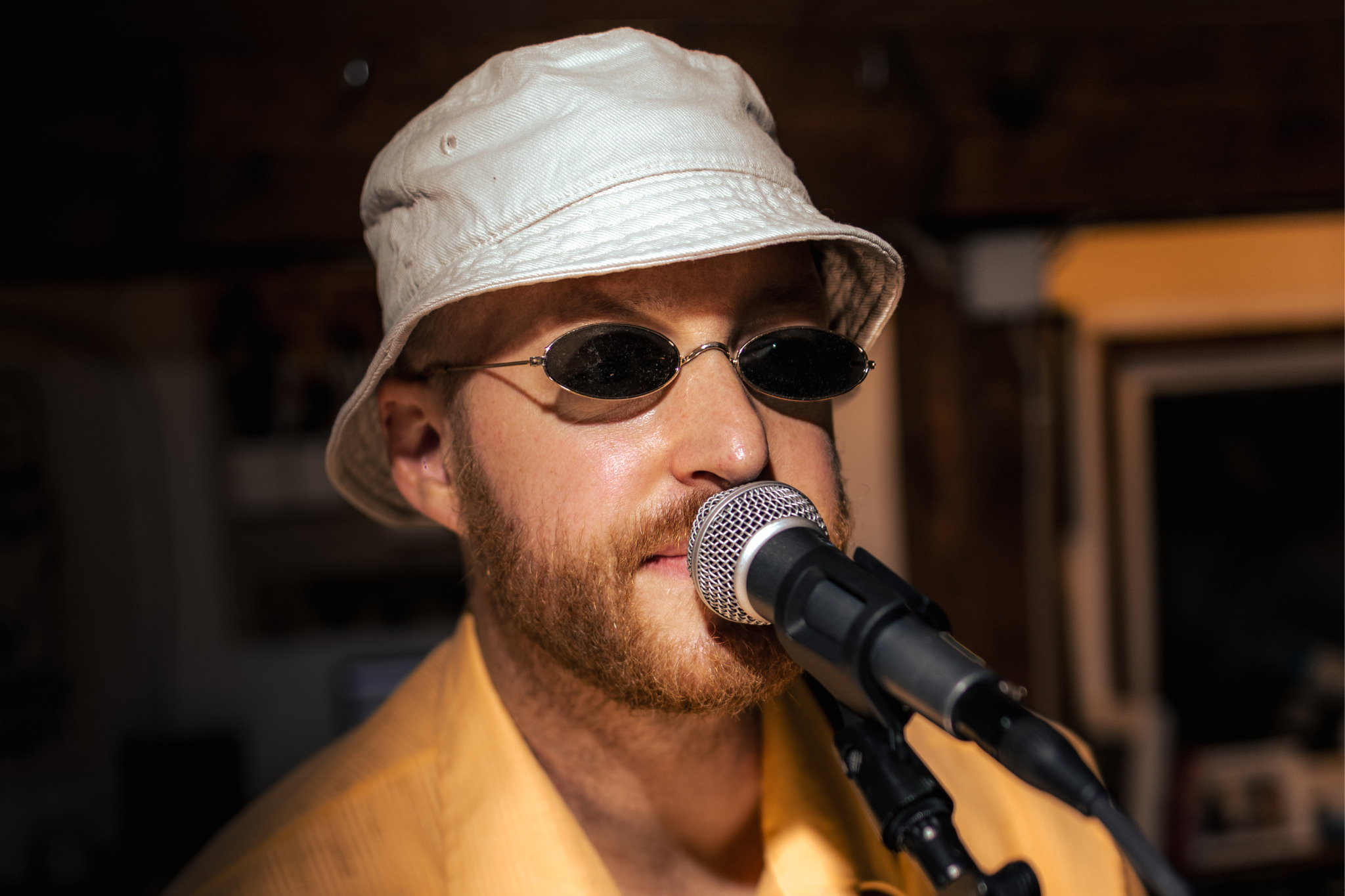 Future Franz mit weißem Hut, Sonnenbrille und gelbem Hemd am Mikrofon.