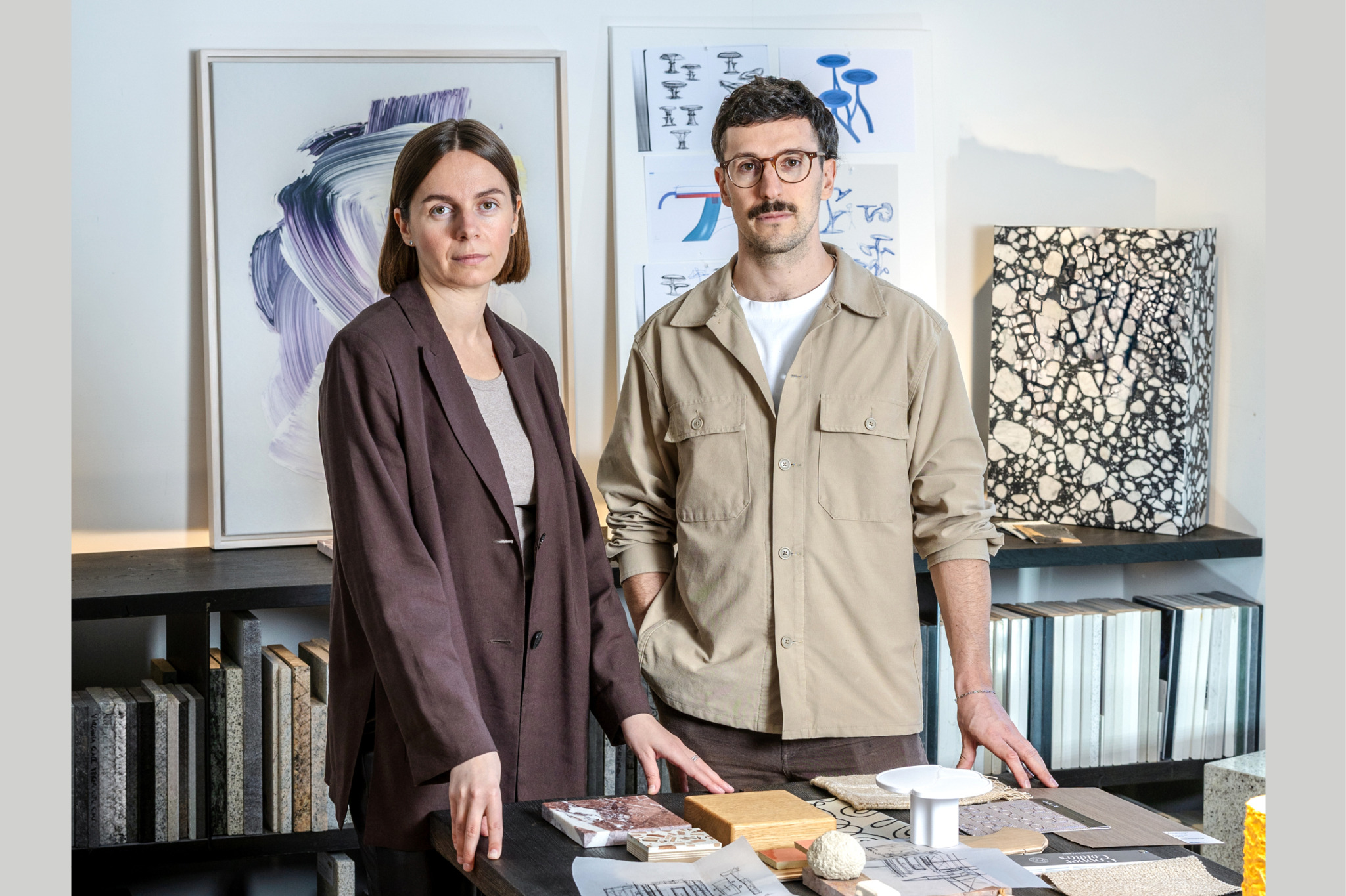 Inna und Marius von Studio Bovti vor Entwürfen und Materialmustern im Studio.