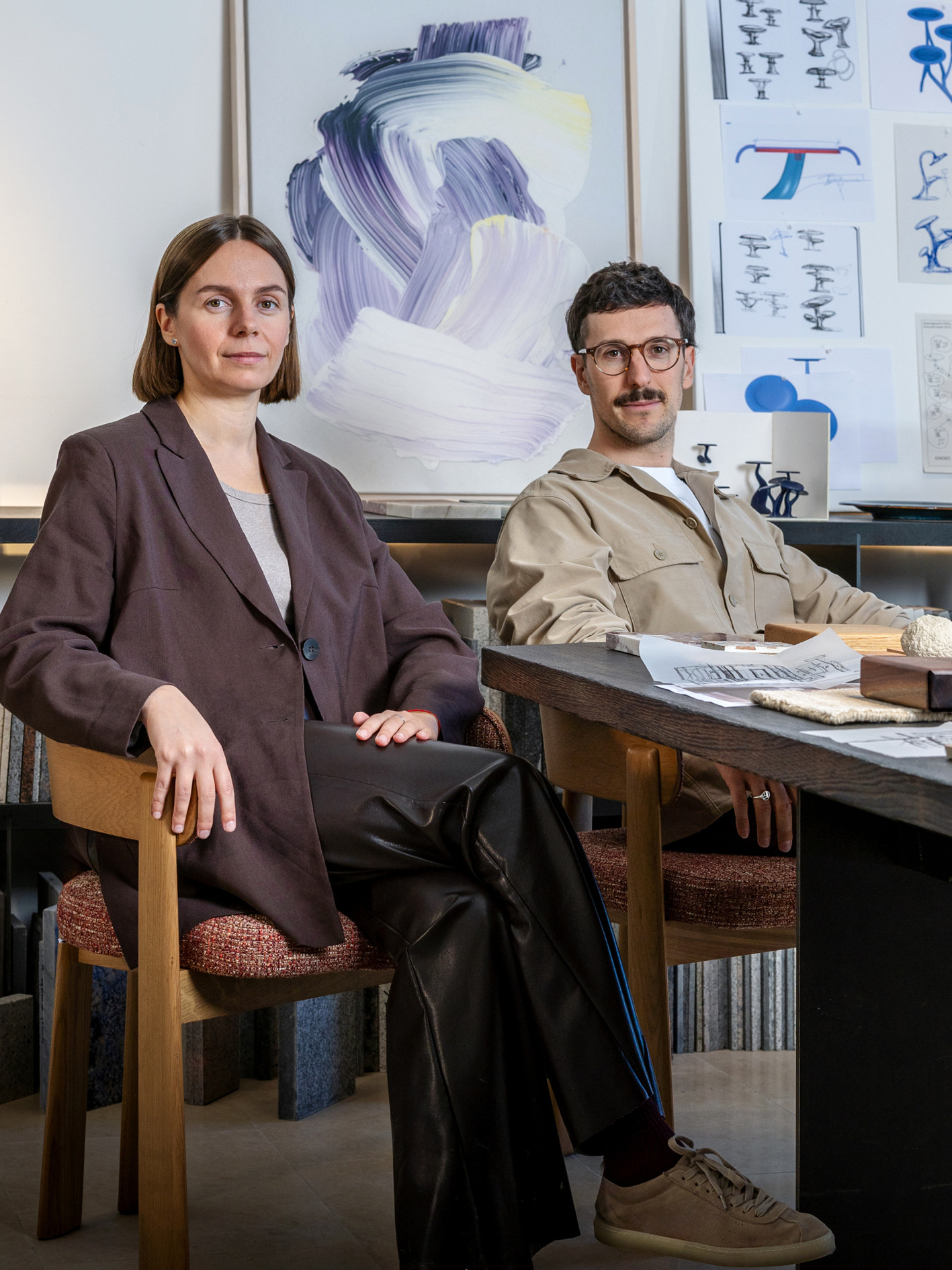 Inna und Marius sitzen am Entwurfstisch vor Skizzen und Modellen im Studio.