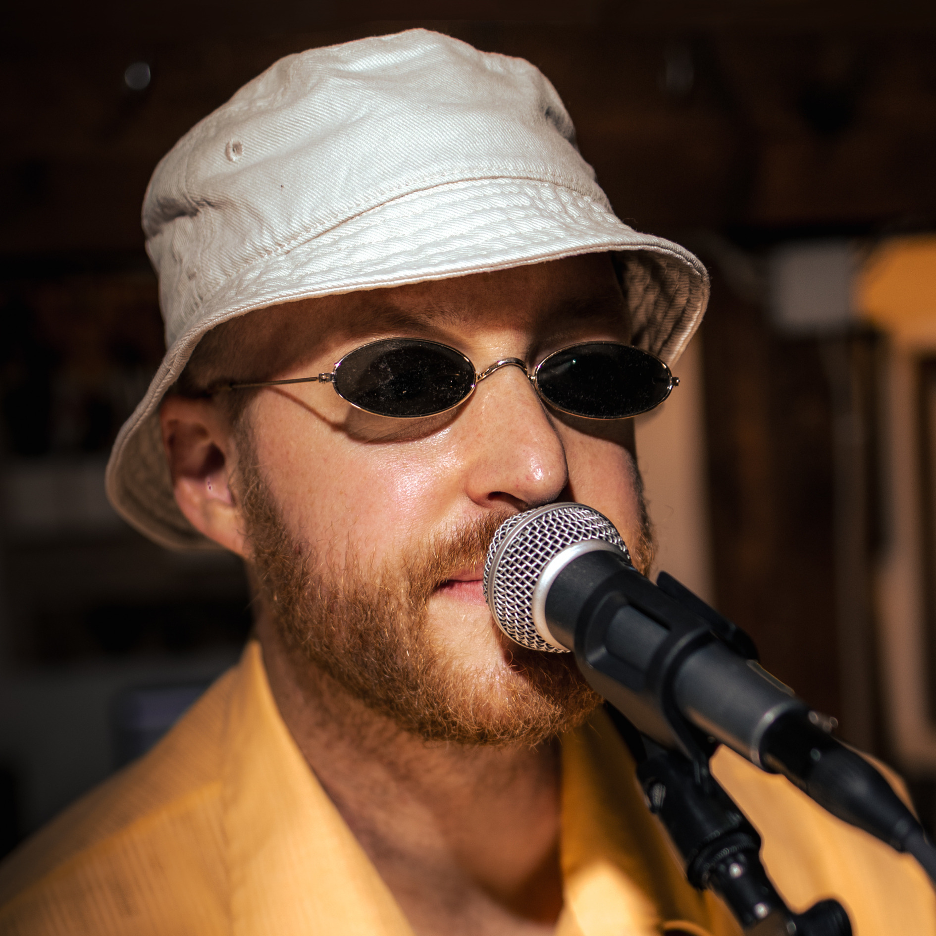 Quadratisches Porträt von Future Franz mit weißem Hut, Sonnenbrille und gelbem Hemd.