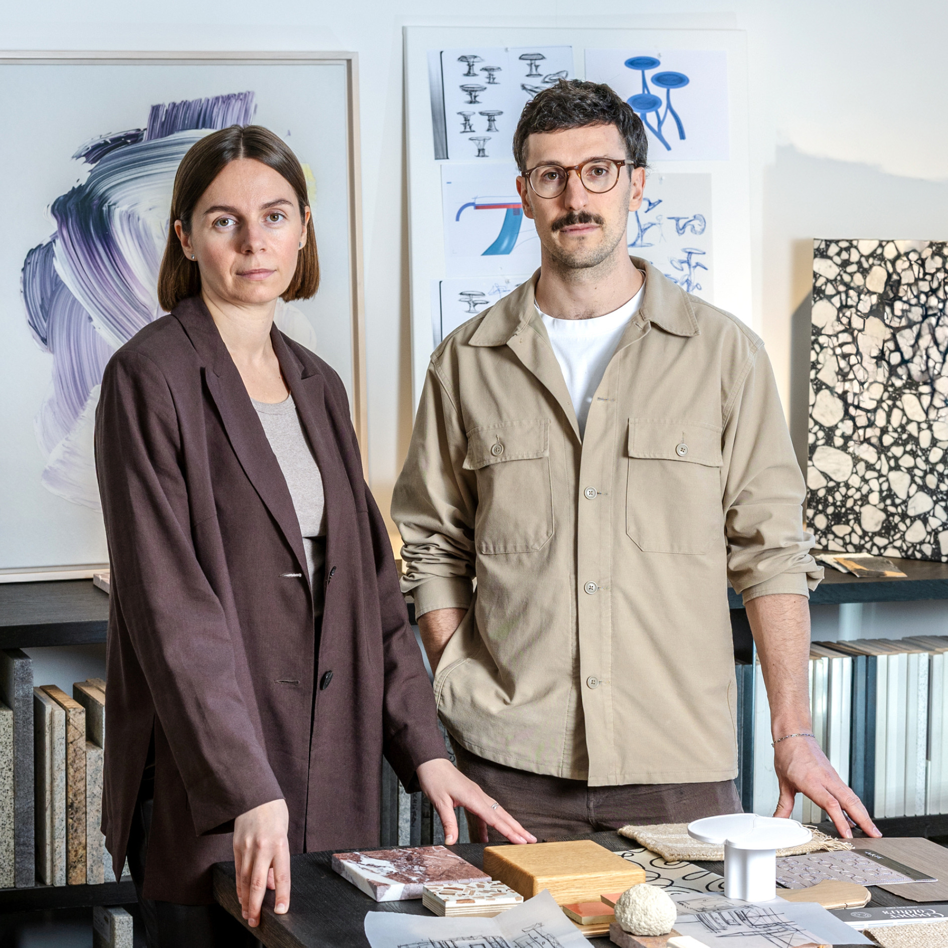Inna und Marius von Studio Bovti vor Entwurfsskizzen und Materialmustern.